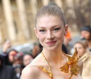 Hunter Schafer smiles wearing a gold neck piece