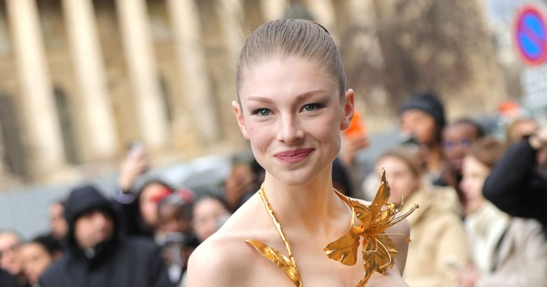 Hunter Schafer smiles wearing a gold neck piece