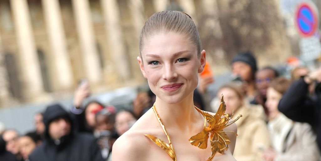 Hunter Schafer smiles wearing a gold neck piece