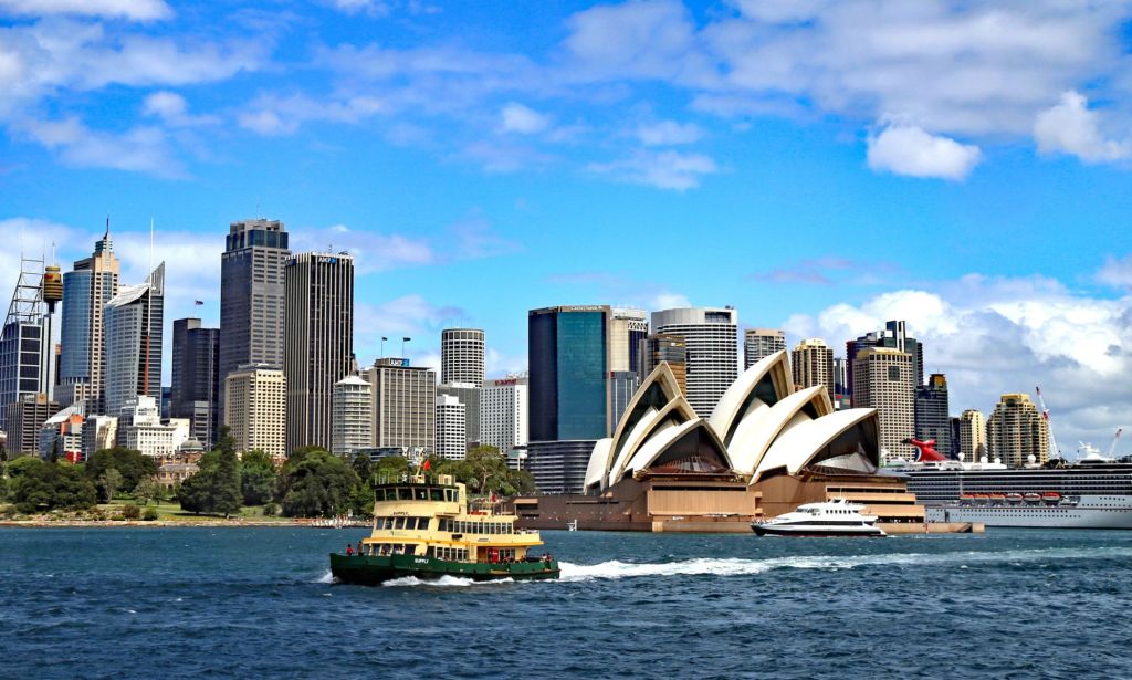 This is an image of the Sydney Harbour in Australia. It is a bright and sunny day, the skyline is visible and the iconic Sydney Opera House is in the bottom right.