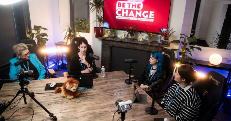 This is an image of a panel discussion. There are 4 speakers in total, and they are sitting at a large table with microphones and cameras set up.