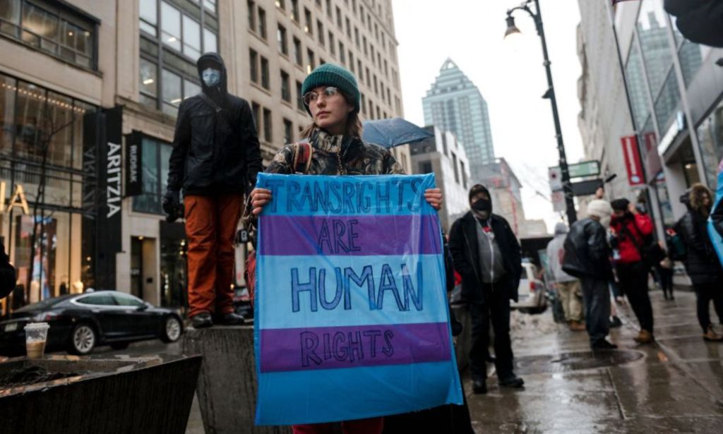 A person holds a sign reading "Trans Rights are Human Rights" as LGBTQ activists protest on March 17, 2023, in front of the US Consulate in Montreal, Canada, calling for transgender and non-binary people be admitted into Canada. - According to police services, some 200 people gathered in the rain to show support for the trans community in the United States.