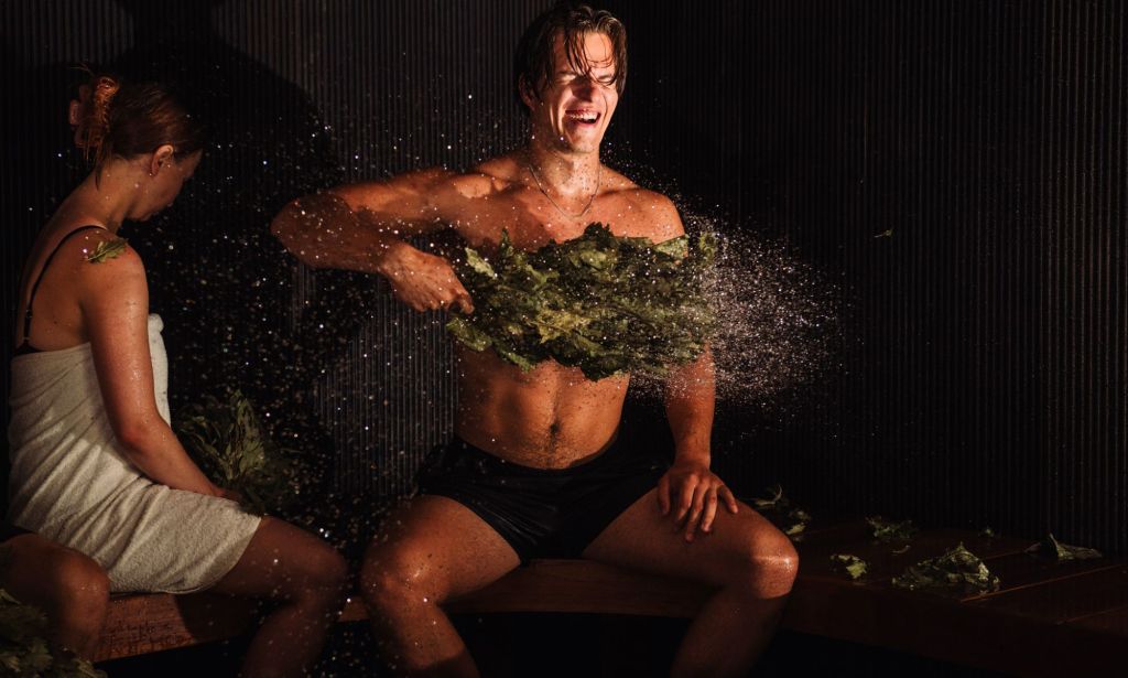 A sauna master slapping tree branches against his chest.