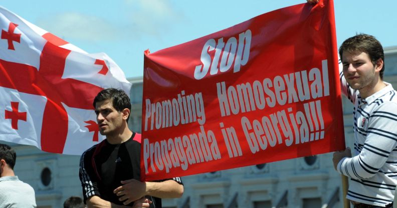 Two men holding up a sign that reads "stop promoting homosexual propaganda in Georgia."