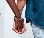 Two men hold hands in public.