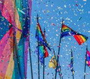 This is an image of confettie flying amongst large Pride flags on a sunny day.