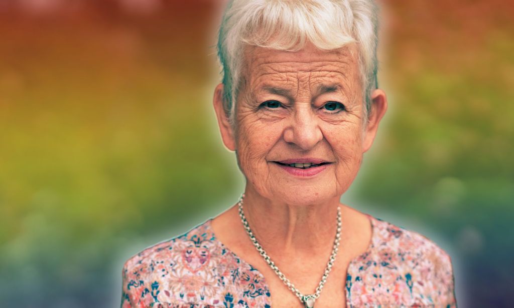 A photoshopped picture of Jacqueline Wilson infront of a rainbow background.