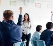 A group of school students raising their hands.