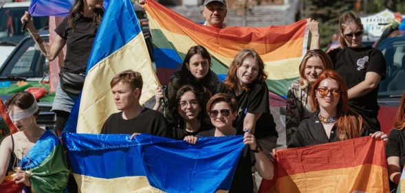 A crowd holding Lesbian, LGBTQ+, and Ukrainian flags.