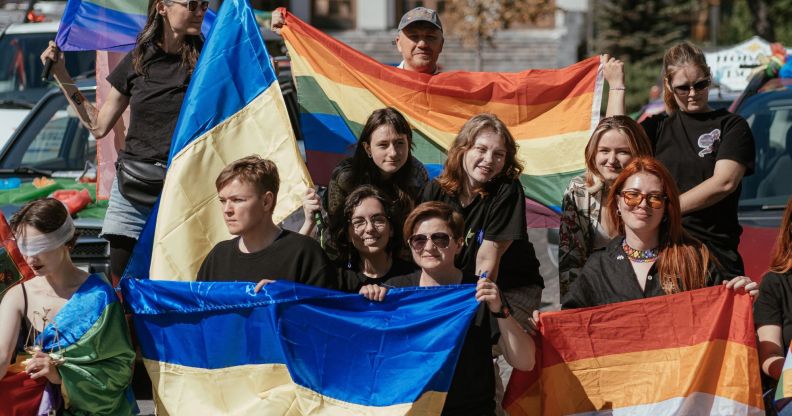 A crowd holding Lesbian, LGBTQ+, and Ukrainian flags.