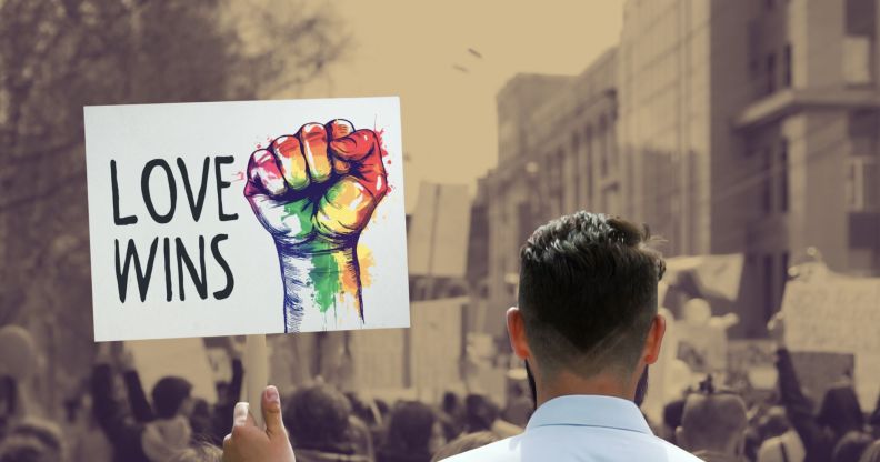 This is an image of someone holding a protest sign that reads "Love Wins" in a protest. The sign is being held by a man with short hair facing away from the camera. The sign is in full colour while the rest of the image is in a sepia tone