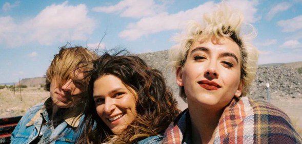 National Anthem still: Charlie Plummer, Eve Lindley, and Mason Alexander Park in the back of a truck wearing denim jackets, their hair blowing in the wind.