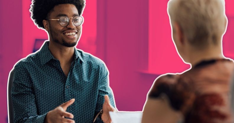 This is an image of a job interview. There is a Black man with glasses speaking to a white women with blond hair.