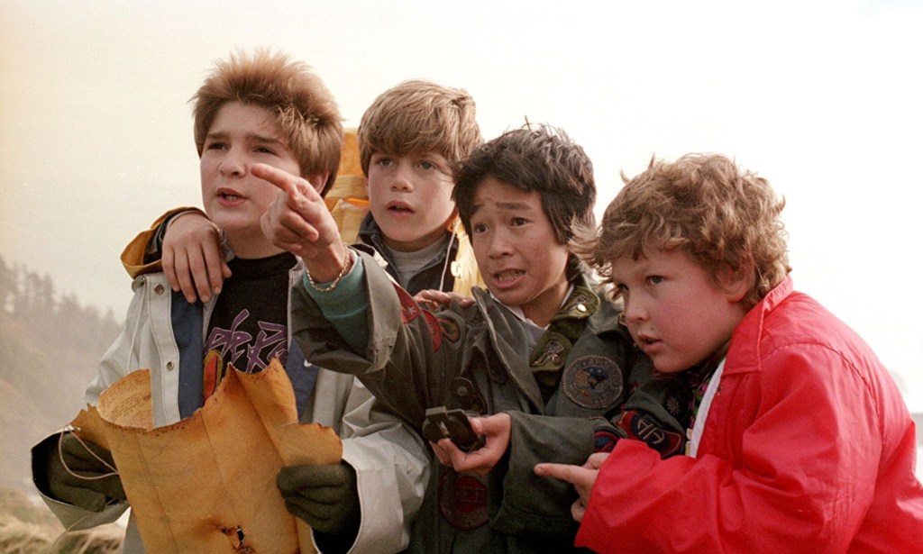 Four young boys in The Goonies look at a map and a compass and try to navigate