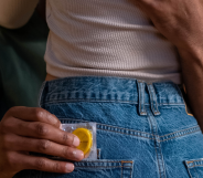 Couple embracing, with one person holding a condom.