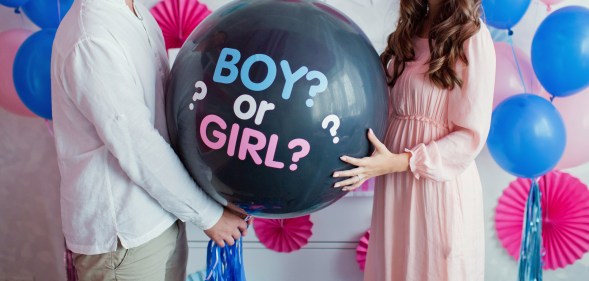 Man and woman holding a balloon with the text Boy or Girl? for a gender reveal party