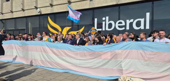 Liberal Democrats party members unfurling giant trans flag outside the Brighton Centre