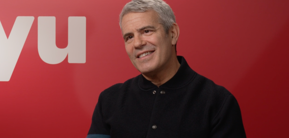 Real Housewives host Andy Cohen in front of a Hayu logo