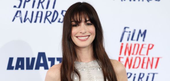 Anne Hathaway smiles on a red carpet in 2024.