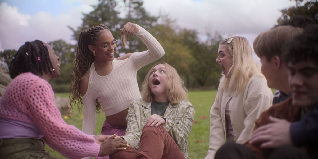 A still from Heartstopper season three featuring Darcy having their hair cut by friends.