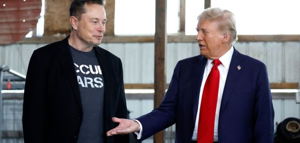 Republican presidential nominee, former President Donald Trump offers his hand to Elon Musk back stage during a campaign rally at the Butler Farm Show grounds on October 05, 2024 in Butler, Pennsylvania