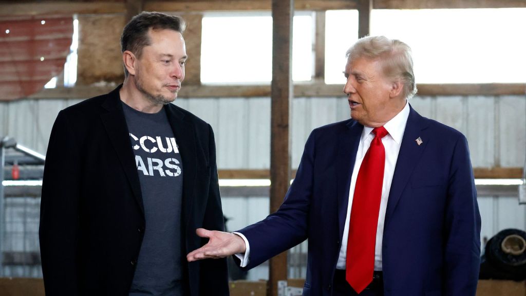 Republican presidential nominee, former President Donald Trump offers his hand to Elon Musk back stage during a campaign rally at the Butler Farm Show grounds on October 05, 2024 in Butler, Pennsylvania