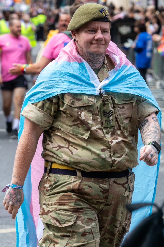 man in camo with a trans flag