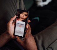 Close up of hands holding a smartphone. The screen shows that they have matched with a femme-presenting young person.