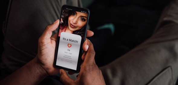 Close up of hands holding a smartphone. The screen shows that they have matched with a femme-presenting young person.