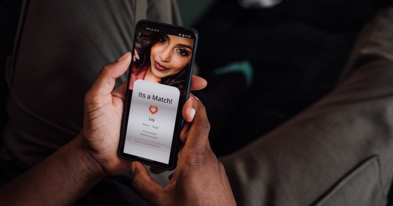 Close up of hands holding a smartphone. The screen shows that they have matched with a femme-presenting young person.