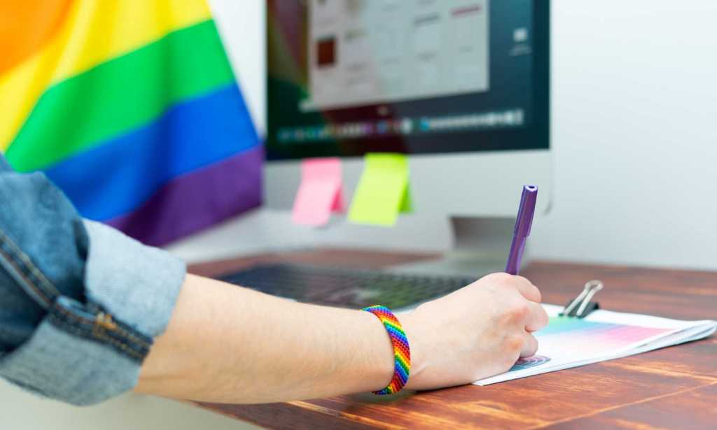 Woman's hand working in office with LGBT decor and accessories. Cultura LGBTQIA