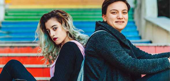 Same sex young female couple hanging out on rainbow steps