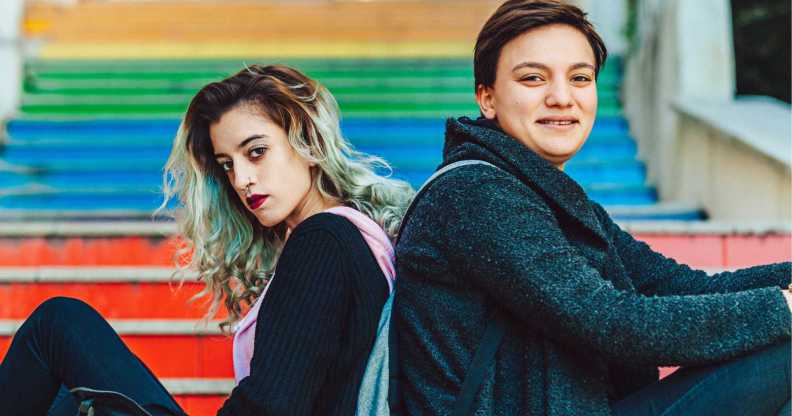 Same sex young female couple hanging out on rainbow steps