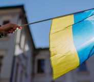 A person holds a Ukrainian flag in a protest against war.