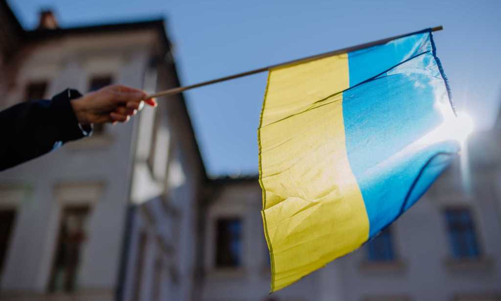 A person holds a Ukrainian flag in a protest against war.