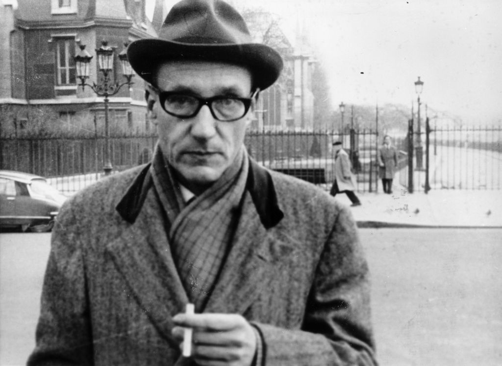 William Burroughs photographed on the street, bundled up and smoking