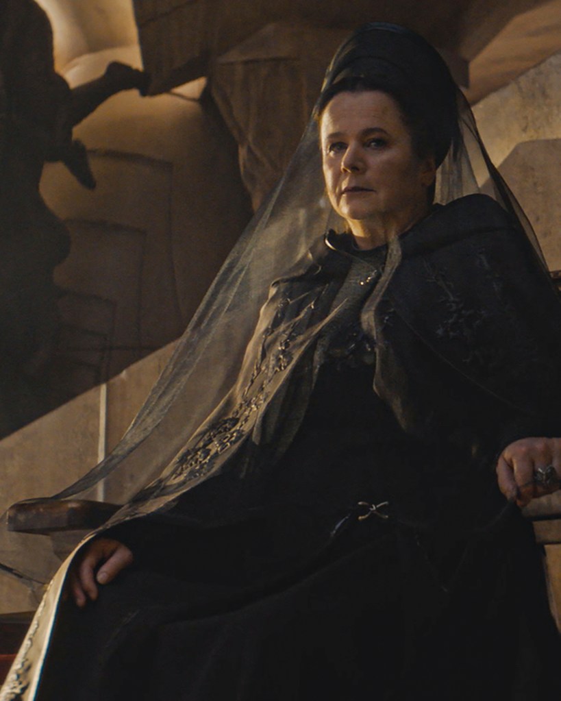 Emily Watson in Dune: Prophecy. She's sat in an all black dress and veil agains a sand coloured wall