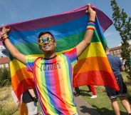 a gay bangladeshi man holding a pride flag in London