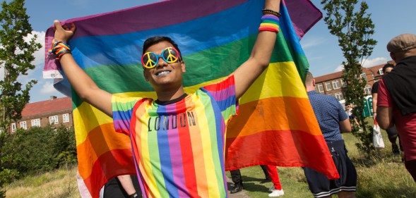 a gay bangladeshi man holding a pride flag in London