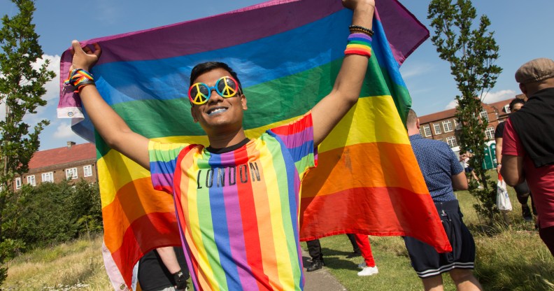 a gay bangladeshi man holding a pride flag in London