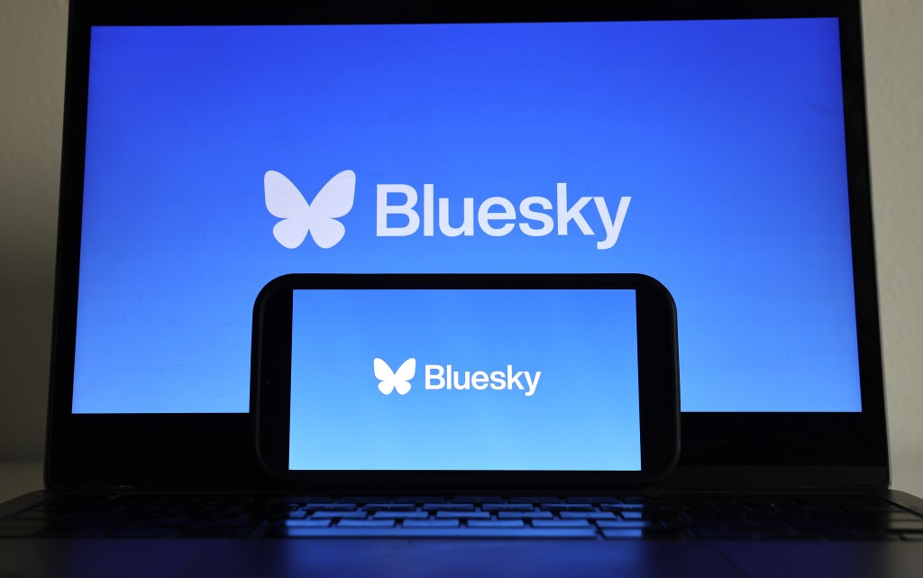 In this photo illustration, the Bluesky logo is displayed on a cell phone and computer monitor