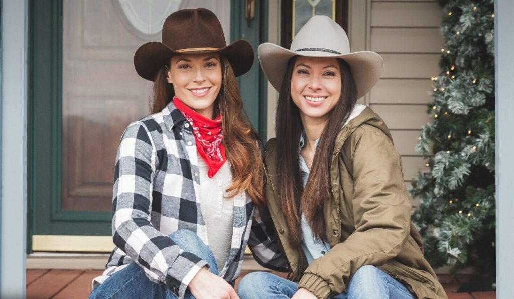 Christmas at the Ranch, two women sitting on a porch, both in cowboy hats.