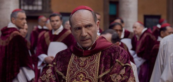 Ralph Fiennes in Conclave as Cardinal Thomas Lawrence in a red and gold robe.