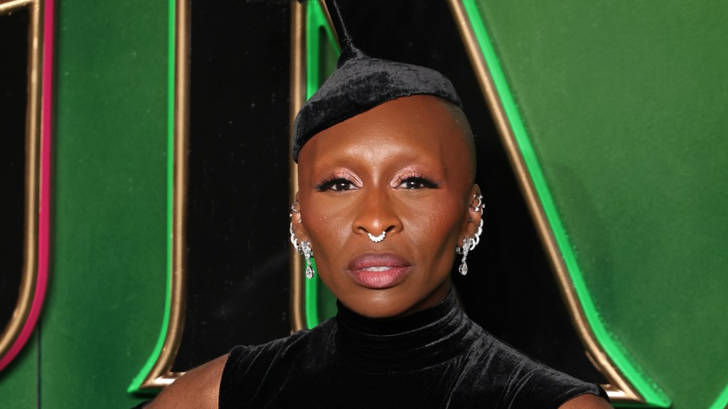 Cynthia Erivo attends the "Wicked: Part One" European Premiere . wearing dark green velvet dress and hat with multiple silver earings.