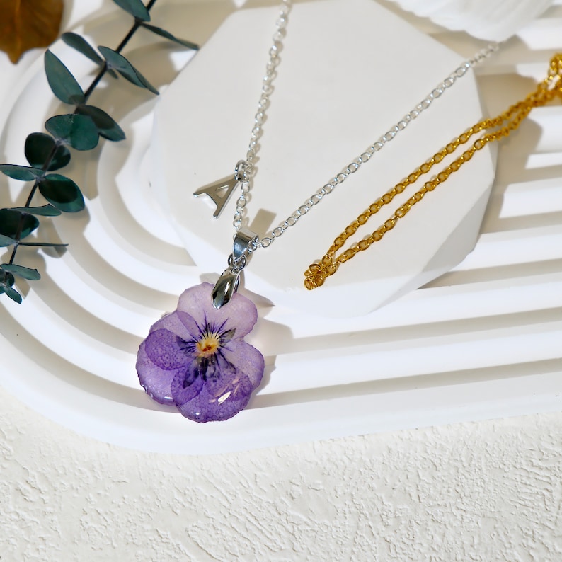 A necklace of a dried violet flower sealed in resin