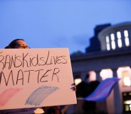 Trans rights activist holding sign which reads, "Trans kids lives matter".