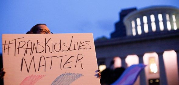 Trans rights activist holding sign which reads, "Trans kids lives matter".