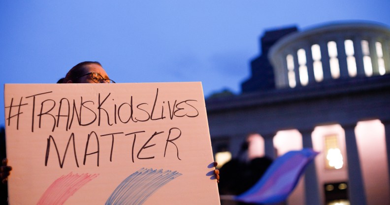 Trans rights activist holding sign which reads, "Trans kids lives matter".