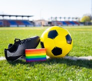 Rainbow colors of LGBTQ+ Pride on an armband next to a football and football boot.