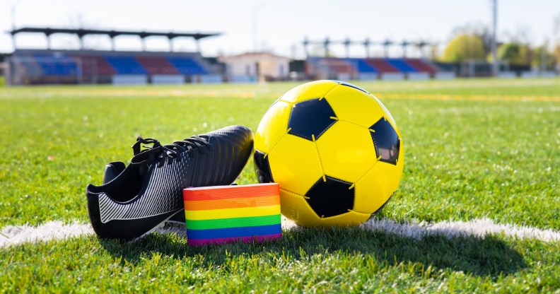 Rainbow colors of LGBTQ+ Pride on an armband next to a football and football boot.